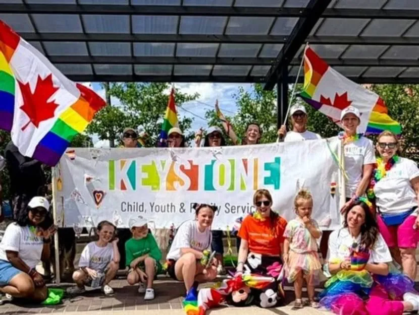 A Keystone group holding a rainbow banner with Canadian rainbow flags at a Pride parade